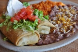 chimichangas with lettuce, tomato, sour cream, beans, and rice